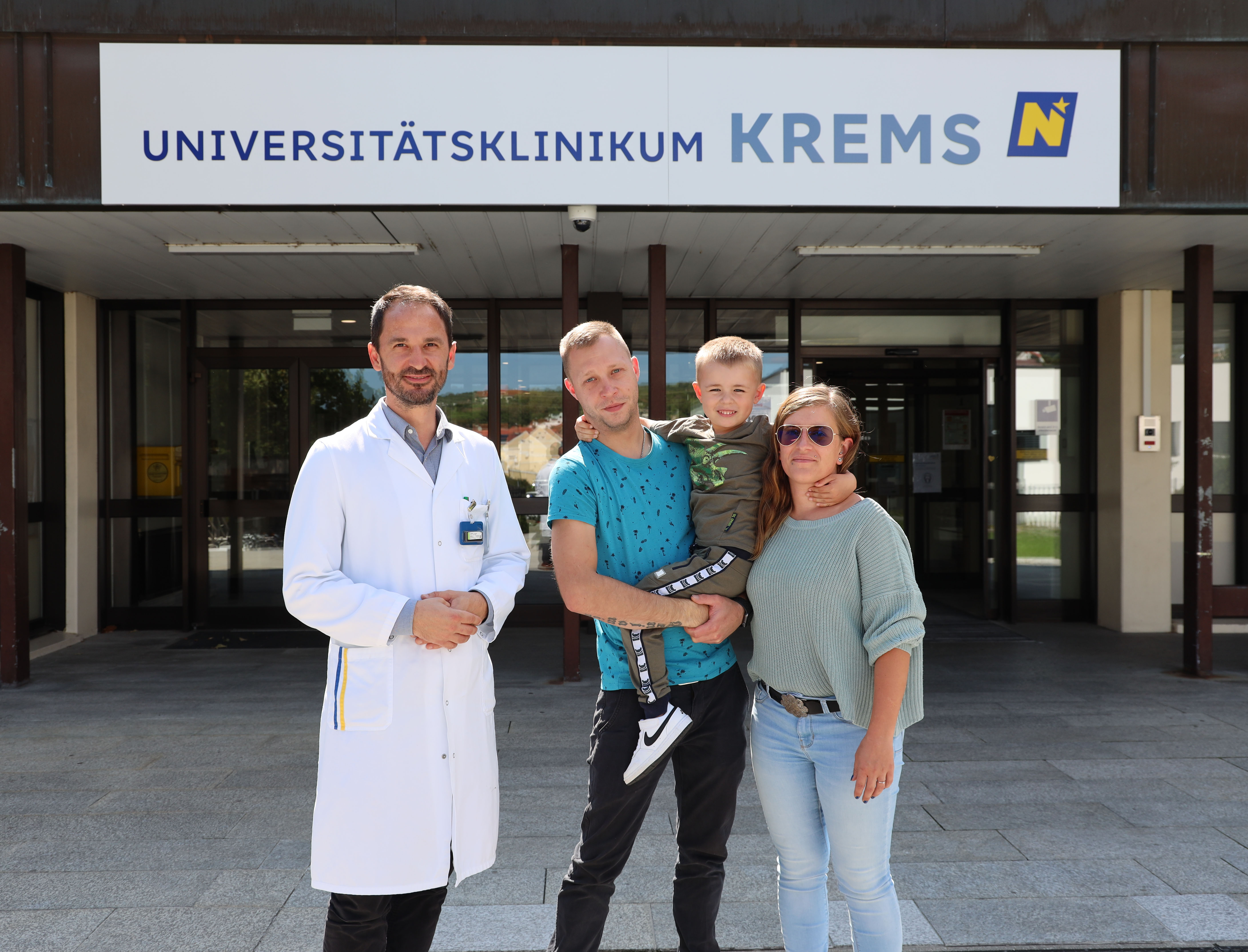 Prim. Dr. Dammerer mit dem kleinen Patienten und seinen Eltern vor dem Klinikum